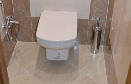 Туалет бежевый – Туалет с темно-бежевой плиткой по периметру и с подвесным унитазом в центре » Дизайн туалета в фото